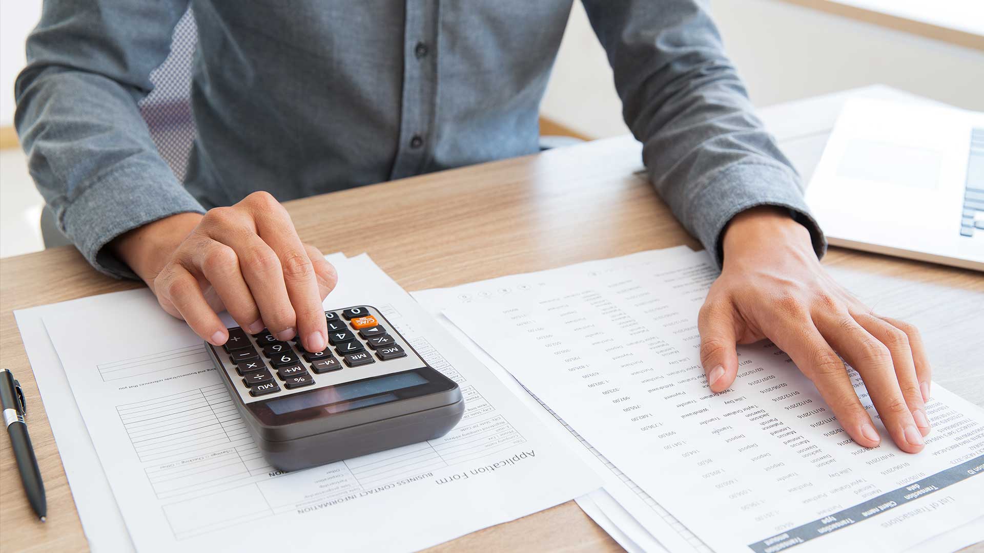Homem a utilizar uma calculadora e a validar os seus cálculos sobre os investimentos.