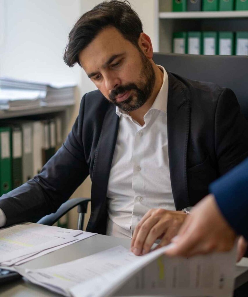 Tiago Ferreira a examinar detalhadamente documentos de um projeto de investimento.