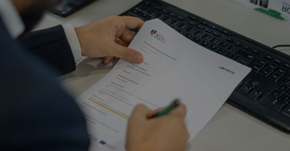 Consultor a analisar documentação técnica de uma candidatura ao programa Portugal 2030 no escritório.