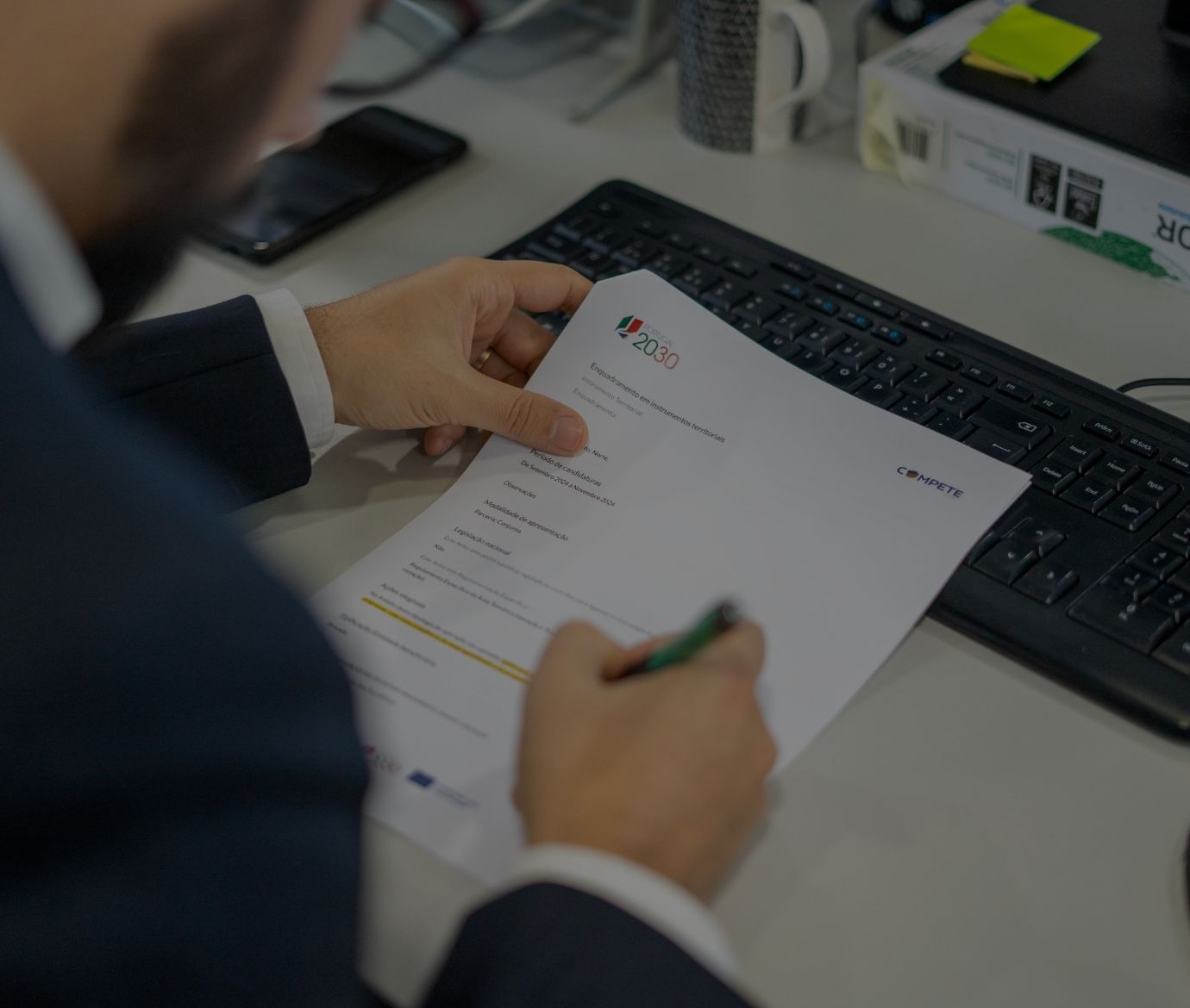 Consultor a analisar documentação técnica de uma candidatura ao programa Portugal 2030 no escritório.
